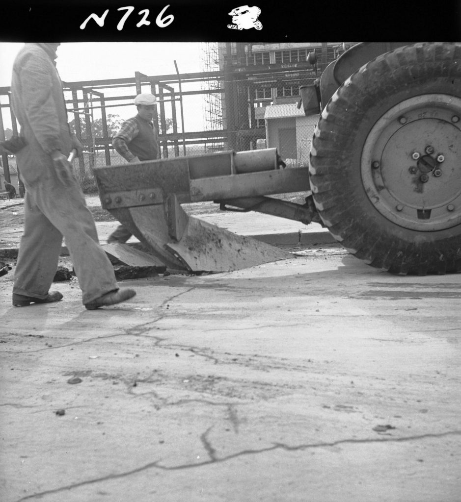 N726 Image showing the ripper attachment of a front end loader ripping asphalt on Flemington Road