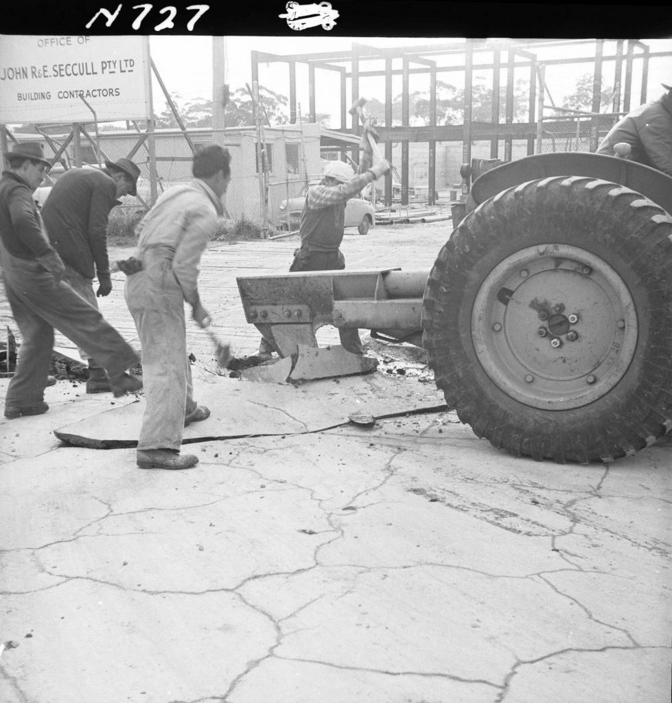 N727 Image showing the ripper attachment of a front end loader ripping asphalt on Flemington Road