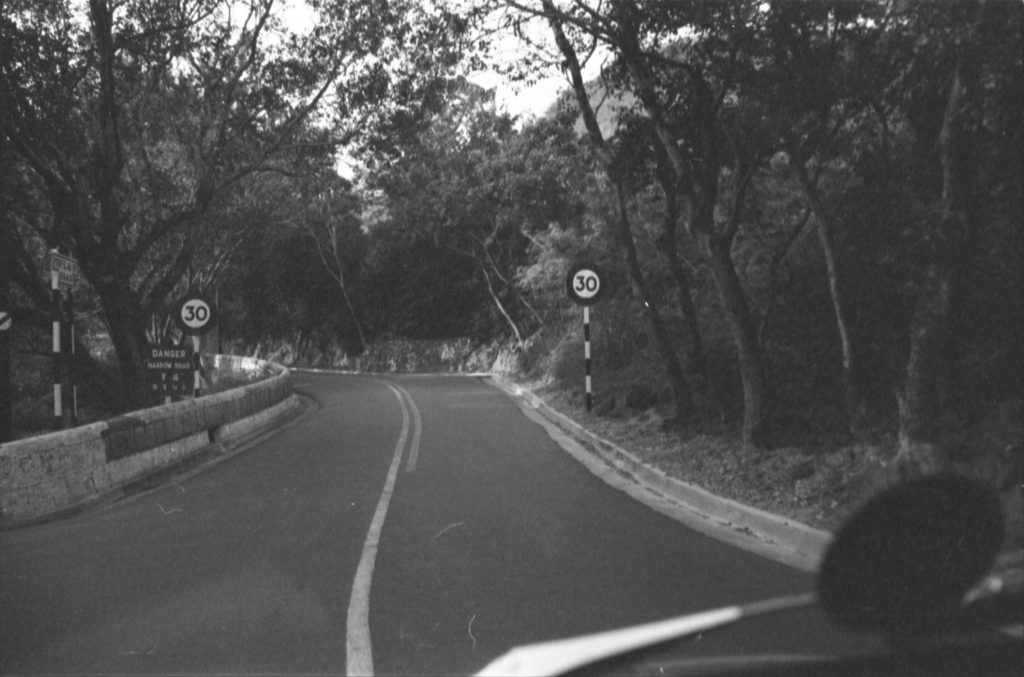 35A-25f Image of a road in Hong Kong, with speed limit signs and a sign marked “danger narrow road”