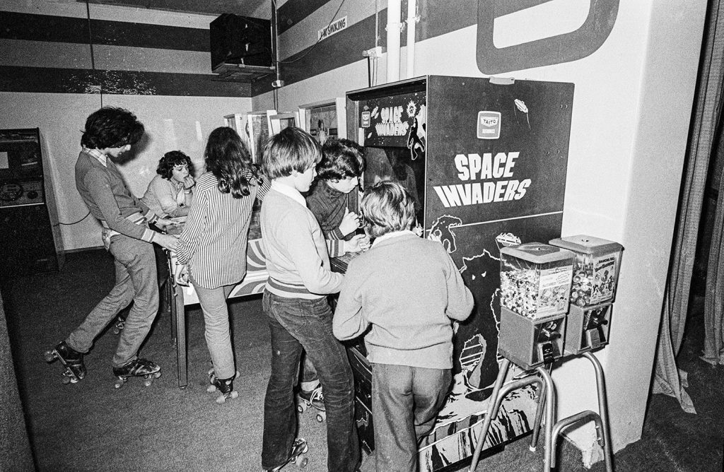 Teenagers playing pinball and Space Invaders